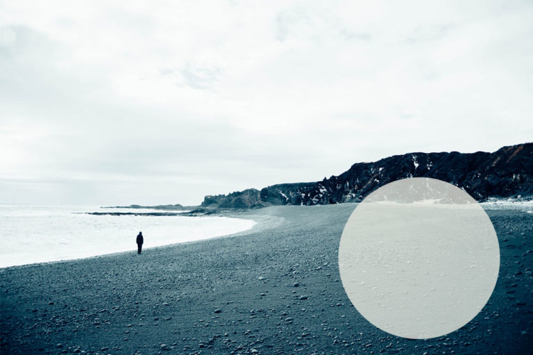 Eine Person, die allein an einem Strand neben dem Ozean in Island steht.