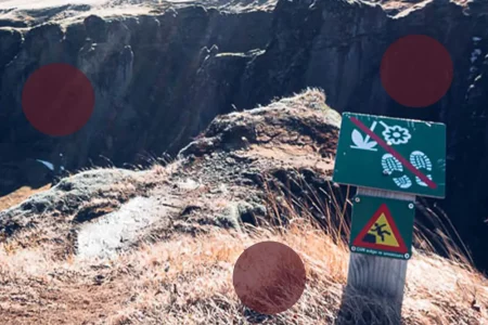 ein Schild an der Seite eines Berges mit roten Kreisen drumherum.