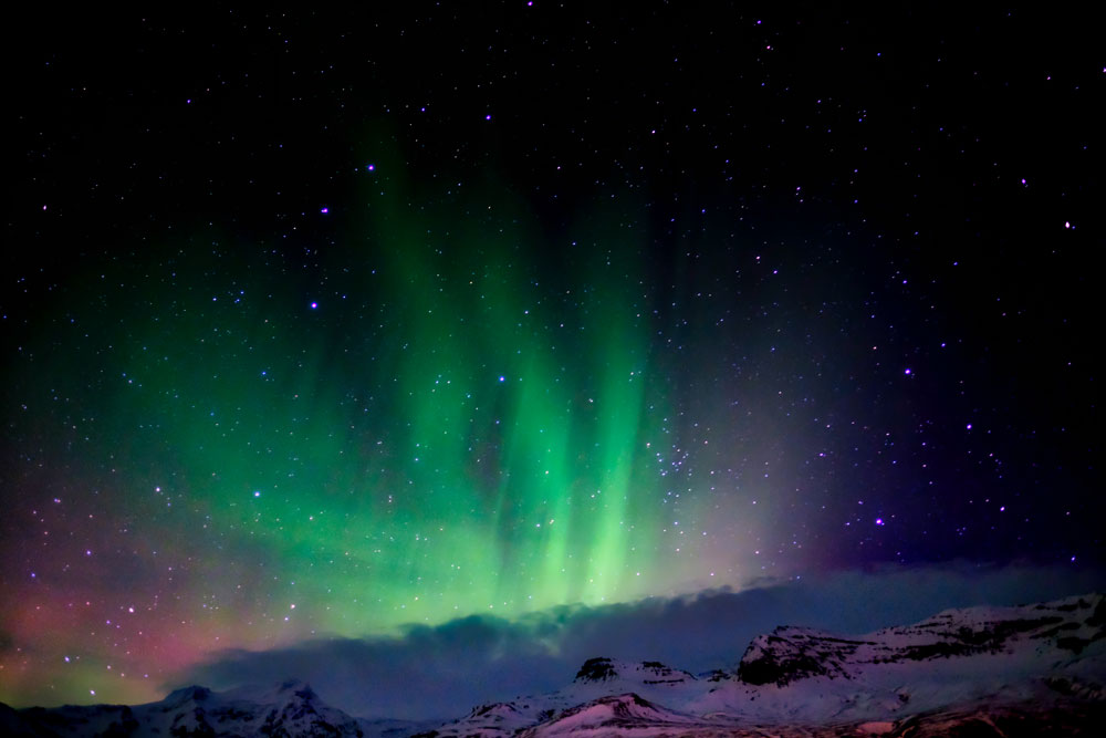 Nordlichter in Island und klarer Sternenhimmel über einer Bergkette 