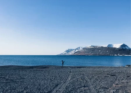eine Person, die an einem Strand mit einem Berg im Hintergrund steht.