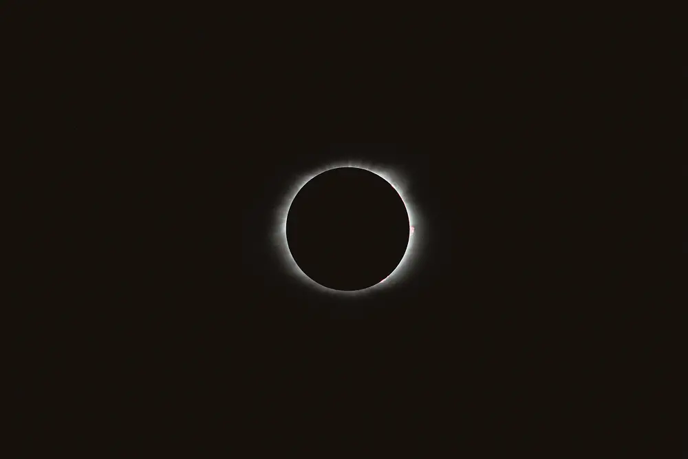 Eine totale Sonnenfinsternis, bei der der Mond die Sonne vollständig verdeckt, so dass nur die Korona der Sonne als schwacher weißer Ring am dunklen Himmel sichtbar ist.